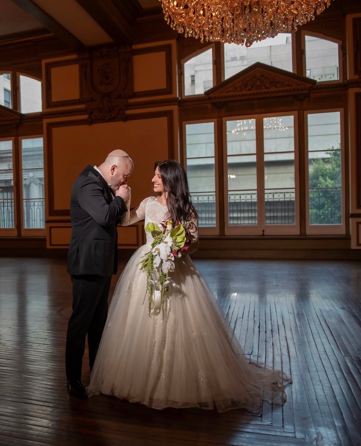 Wedding couple in ballroom with cascading floral bouquet